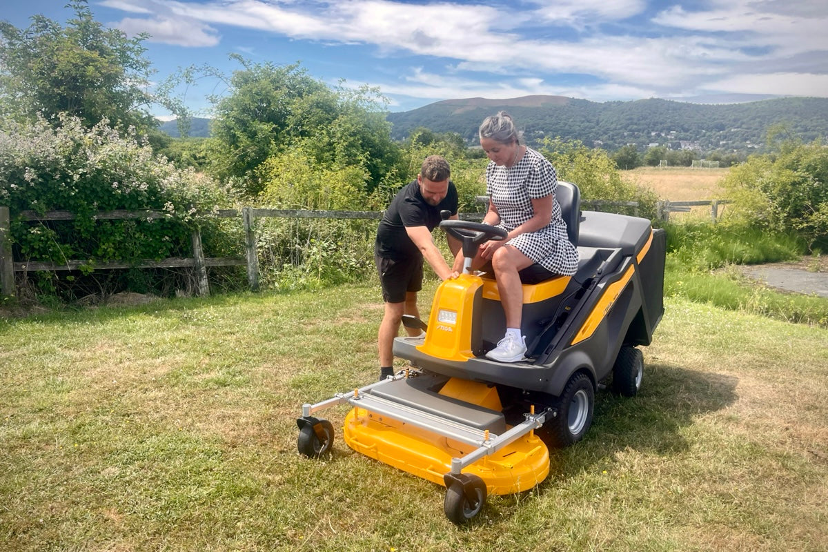 A member of staff demonstrating a ride on mower to a customer